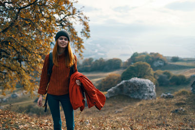 Young woman standing against trees