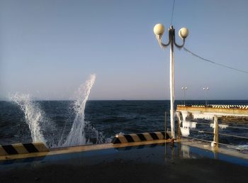 Sea waves splashing on shore against clear sky