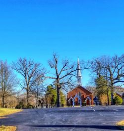 Road leading towards temple against clear blue sky