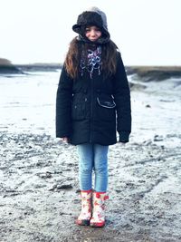 Full length of girl standing on snow covered beach