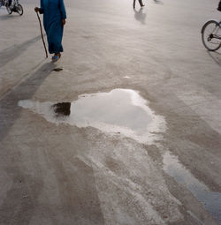 Low section of woman walking by puddle on road