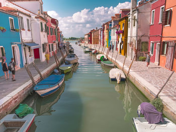 Boats in canal amidst buildings against sky