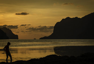 Silhouette person on beach against sky during sunset