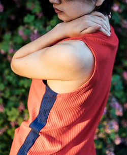 Midsection of woman in red tank top standing outdoors