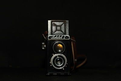 Close-up of old camera against black background