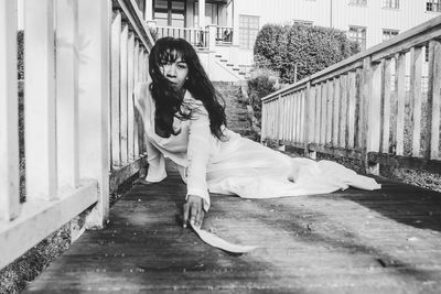 Full length portrait of young woman standing against railing