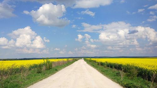 Road amidst field against sky