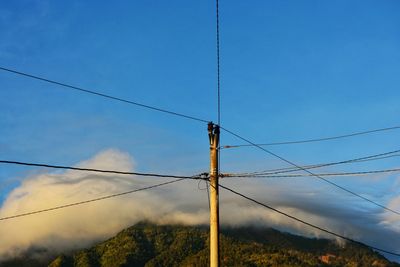 Low angle view of electricity pylon against blue sky