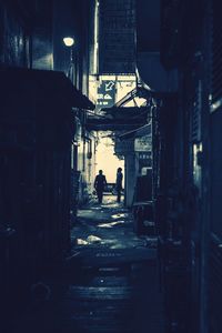 Rear view of silhouette people walking in alley