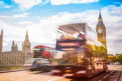 Vehicles on tower bridge against cloudy sky