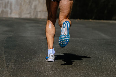 Low section of man skateboarding on road