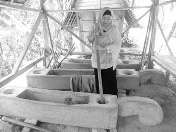 Woman wearing hijab crushing food in wooden object