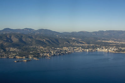 Aerial view of city by sea against clear blue sky