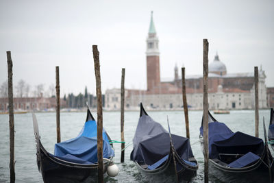 Boats moored in canal with city in background