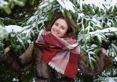 Portrait of woman standing against snowy tree