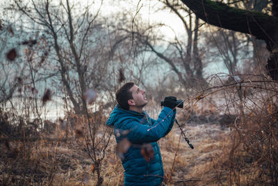 Full length of man standing by bare tree in forest