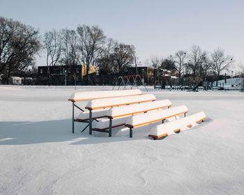 Empty benches in winter against clear sky
