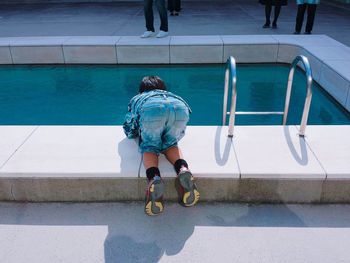 Rear view of boy looking in swimming pool