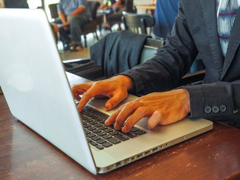 Midsection of man using laptop on table