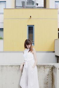 Young woman standing against retaining wall