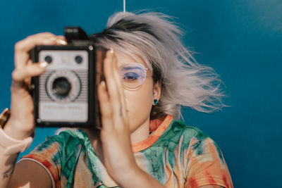 A young woman taking pictures with an analog camera in a colorful dress
