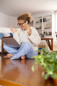 Side view of boy sitting on hardwood floor at home