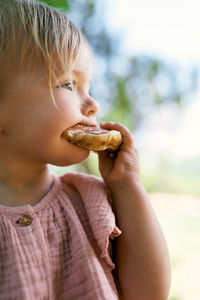 Cute girl eating food sitting outdoors