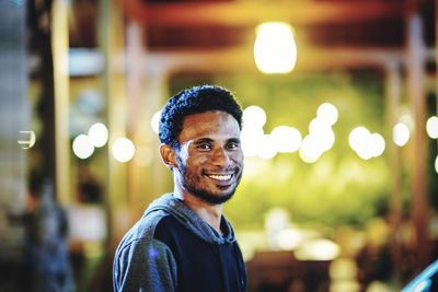 Portrait of smiling man standing illuminated restaurant at night