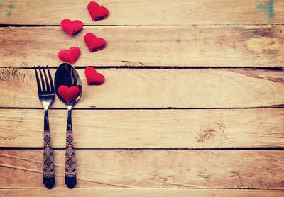 Directly above shot of spoon and fork with heart shapes on wooden table