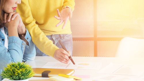 Midsection of business people discussing graphs at desk in office