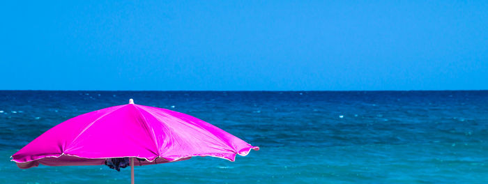 Umbrella on beach against clear blue sky