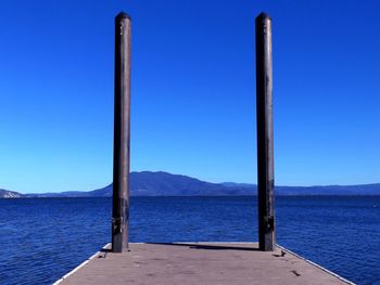 Metallic bollards on pier in lake against blue sky