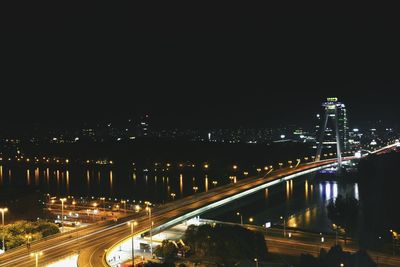 Illuminated bridge over river in city against sky at night