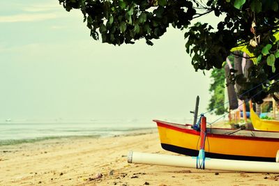 Boat moored on beach against sky