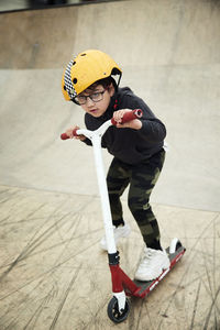 Boy learning how to ride push scooter in indoor skatepark