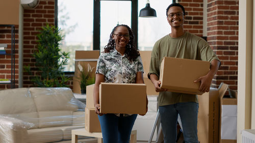 Man and woman holding cardboard boxes at home