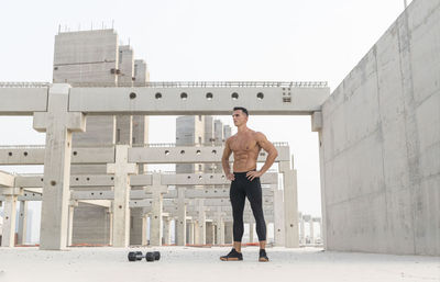 Full length of shirtless man standing against buildings