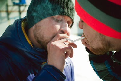 Close-up of men in warm clothing smoking cigarette