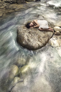 High angle view of man lying on rock at sea shore