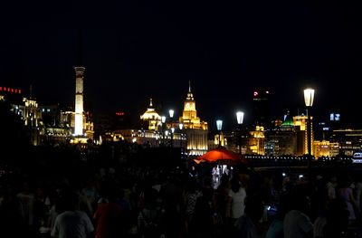 Crowd at illuminated city against sky at night