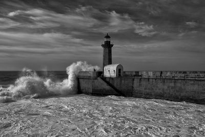 Lighthouse by sea against sky