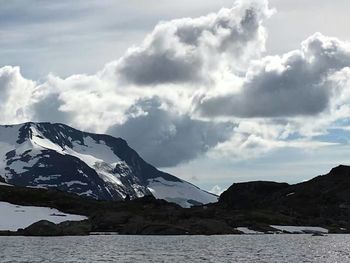 Scenic view of snow covered mountains against cloudy sky