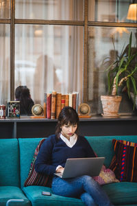 Confident businesswoman using laptop on sofa at creative office