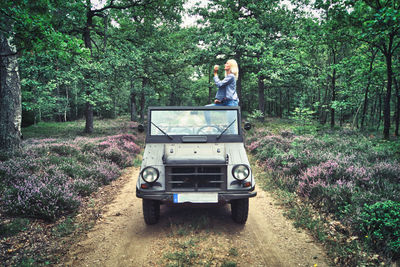 Woman standing in vehicle at forest