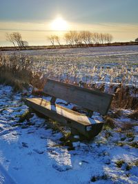 Scenic view of snow covered field against sky during sunset