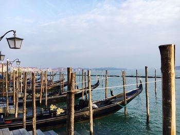 Wooden posts in sea against sky