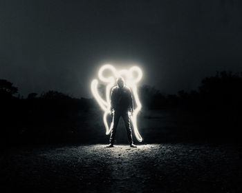 Man standing by light painting on field at night