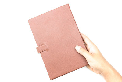 Close-up of hand holding book against white background