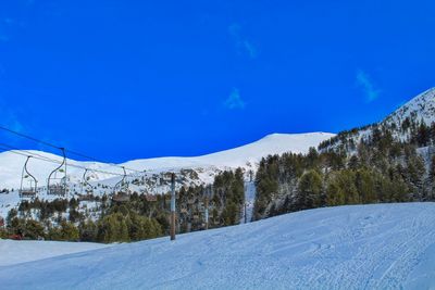 Scenic view of snow covered mountains against clear blue sky