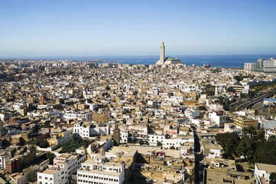 Aerial view of city by sea against clear sky